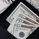 Stack of dollars and black envelope with banknotes inside